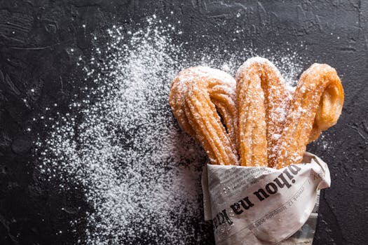 pexels-photo-372851-372851 Close-up of freshly baked churros with powdered sugar on newspaper. A tasty dessert treat.